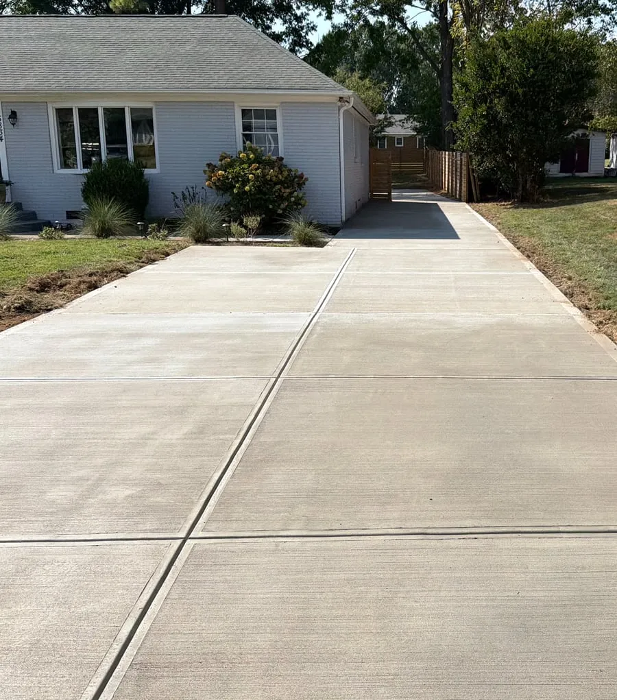 New concrete driveway alongside a white home
