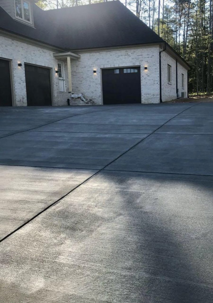 A wide finished driveway running up to a three car garage